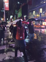 people with umbrellas walking at night in NYC 