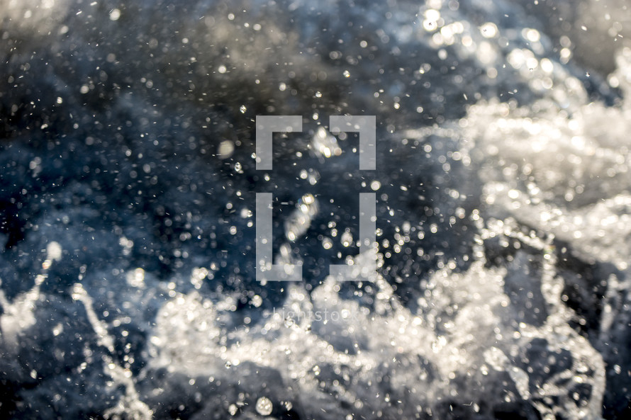 Splashing water particles as waves are crashing on the shore of a beach