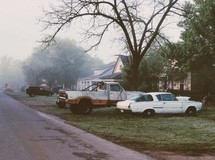 cars parked in the grass in front of a house 