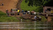 boats on a shore and people walking in a dirt road in Uganda 