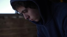 A troubled young man, sad teenage boy anxious, depressed, sitting alone.