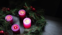 Advent wreath with all four candles burning in a dark room shot from above
