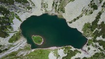 Glacial mountain lake with a green island, in the heart of the Carpathian mountains of Romania
