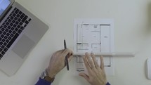 architect draws a building plan, measures the dimensions of the blueprint with a ruler 

