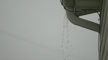 Water pours from house rooftop during heavy rain storm during the summer.