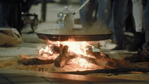 The preparation of the spanish dish paella in the evening, over an open fire, on the street during the celebration of Fallas in Valencia, Spain