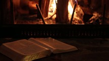 Bible in front of a fire in a hearth 
