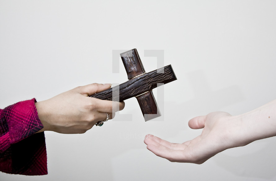 Sharing the faith; one person handing a cross to another.