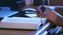 A man writing notes from Bible study at desk