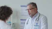 Doctor Having Discussion with Colleague at Work in Medical Office
