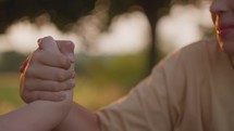 Close up of two teenagers engaged in arm wrestling outdoors