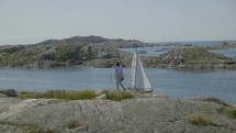 girl walks through swedish archipelago with passing sailboat in skarhamn