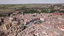 Aerial View Over Plaza Mayor Beside Segovia Cathedral On Sunny Day With Rural Fields In Distant Background. Orbit Motion	