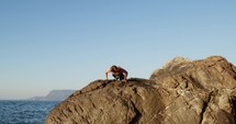 Boy training push up on the rocks near the ocean