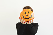 a person holding up a jack-o-lantern 