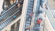 Time lapse of people riding escalators in a shopping mall.