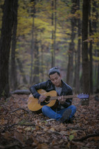 man playing a guitar in the woods 
