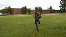 A young woman walking to class on a college campus