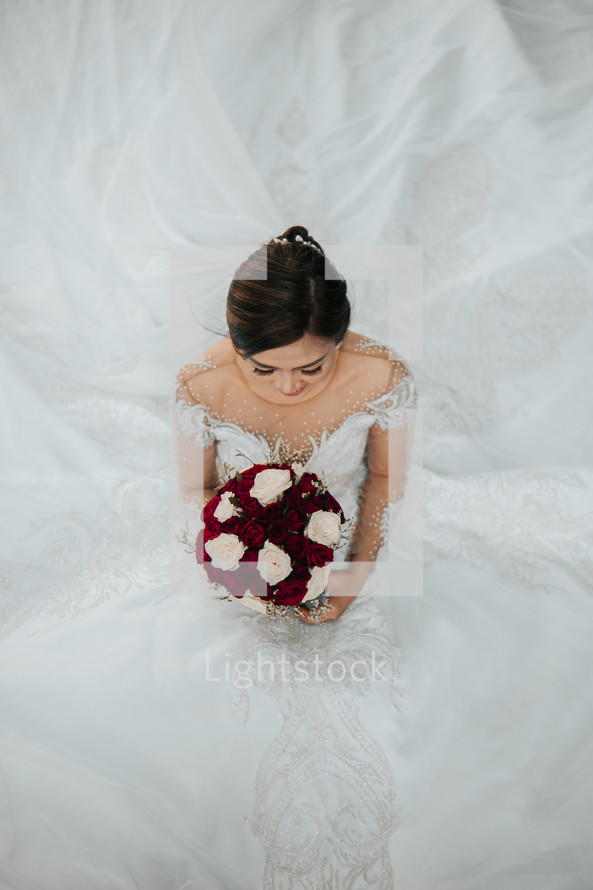 portrait of a bride holding a bouquet of red and white roses 