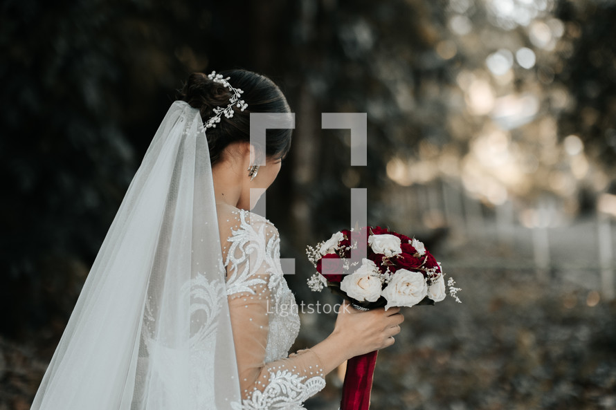 bride holding a bouquet of red and white roses 