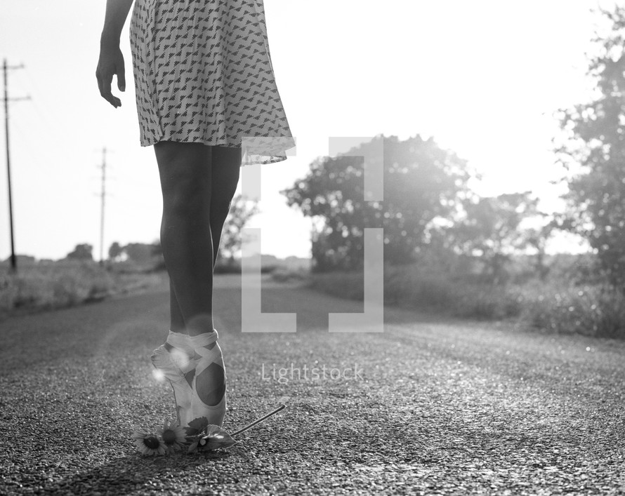 ballerina in toe shoes on a gravel road 
