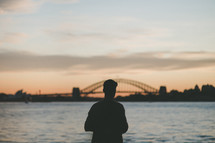 silhouette of a man standing in front of a bridge 