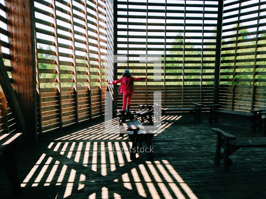 a child walking on a bench in a barn 