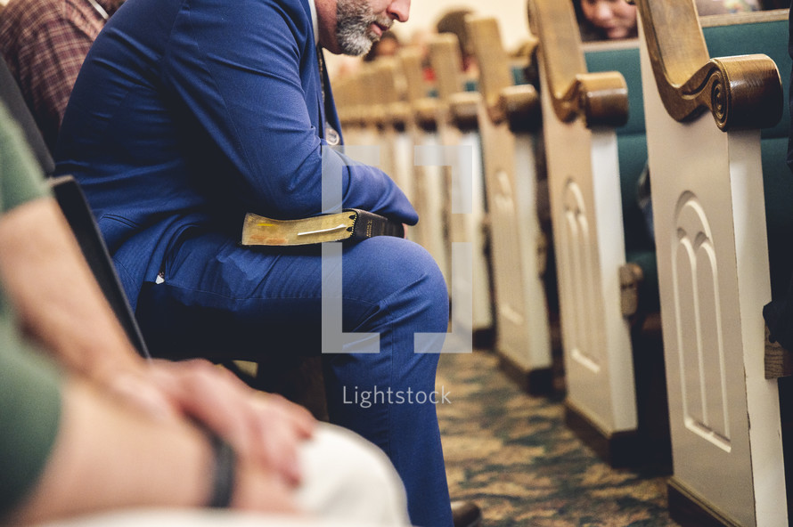 people sitting in pews holding Bibles 