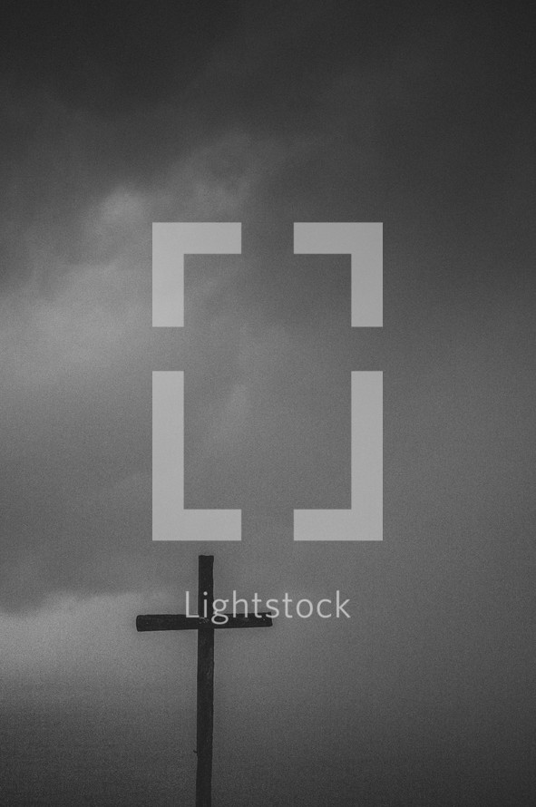 Silhouette of a wooden cross under a stormy sky.