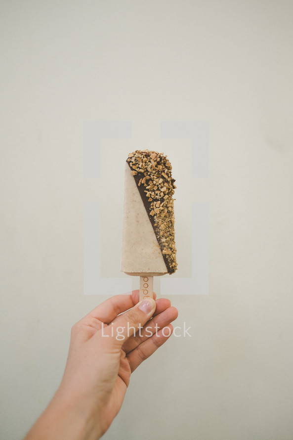 A hand holding an ice cream bar.