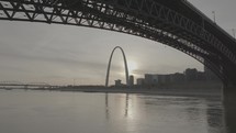View of Saint Louis, Missouri arch over the Mississippi river and under a bridge.