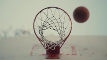 Close up of a basketball being shot on an outdoor basketball court on a sunny day