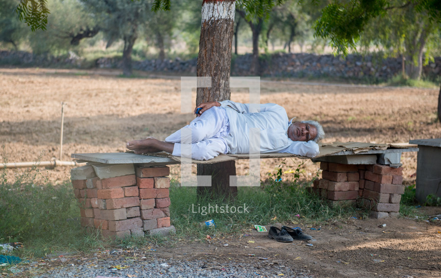 a man sleeping on a bench in Mandawa, India 