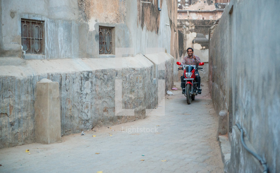 man on a motorcycle on a narrow alley in India 