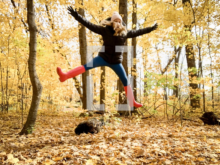woman jumping in fall leaves