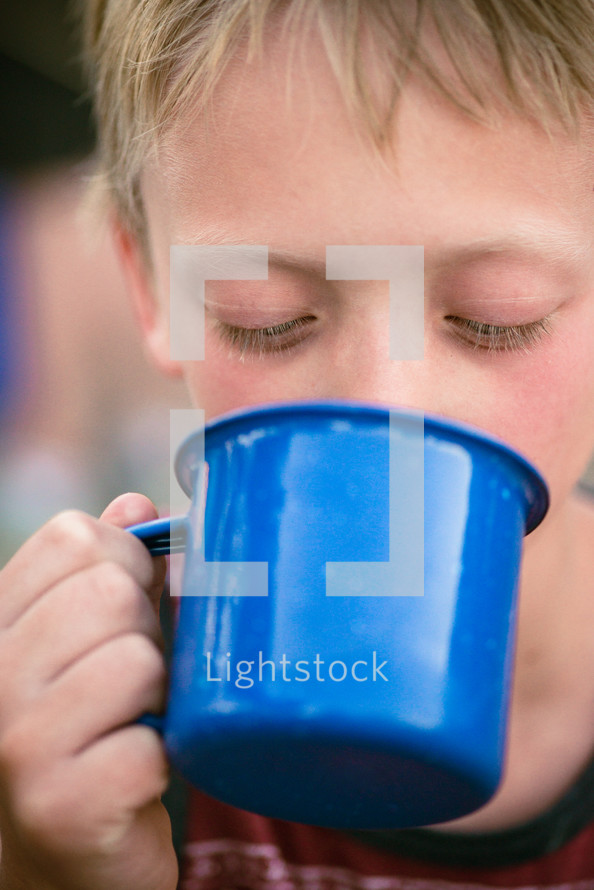 a boy drinking from a mug 