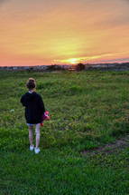 girl standing a skateboard looking out at the sunset over the intracoastal waterway with copy space 