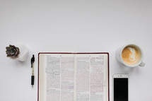 open Bible, pen, succulent plant, latte, and iPhone 