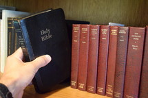 a man taking a Bible off a shelf 