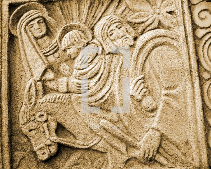 A stone carving of Jesus, Mary and Joseph on a donkey. The artwork is representative of a Mayan or Aztec Indian carved relief depicting a young Jesus travelling with his mother and father through Jerusalem. 