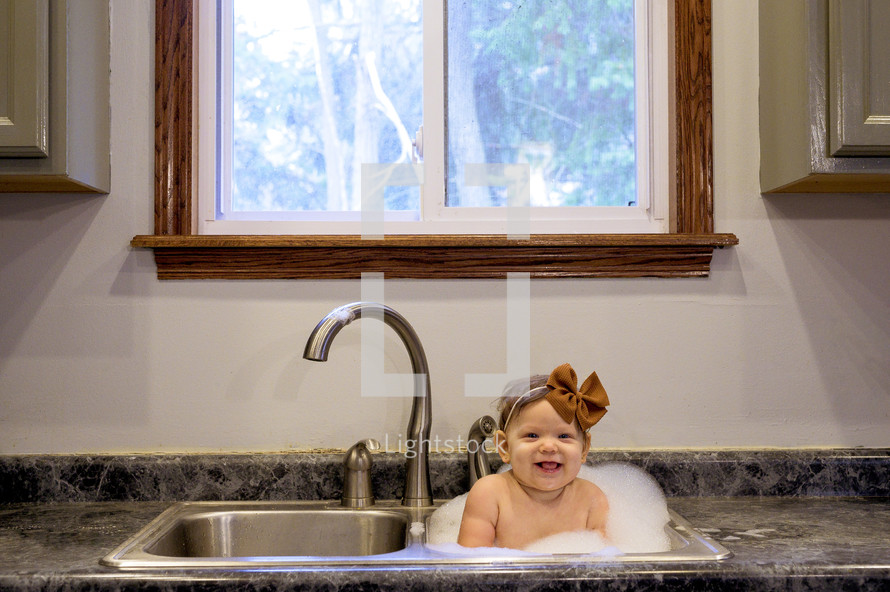 baby bathing in a sink 