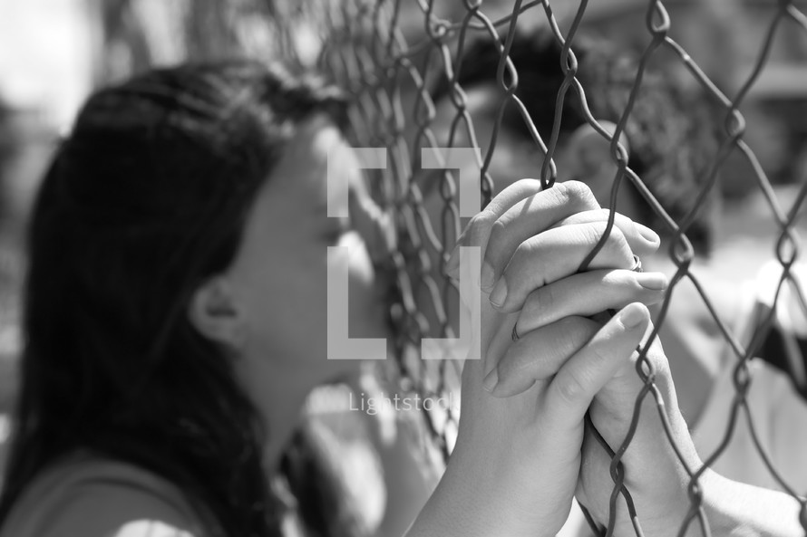 couple kissing through a chain linked fence