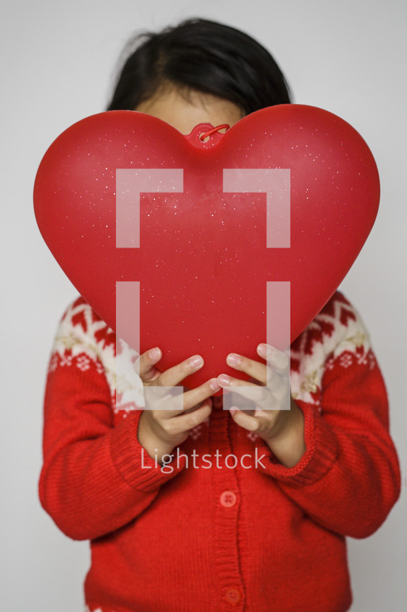 a child in a red sweater holding a red heart