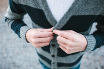 a man fastening a button on his sweater 