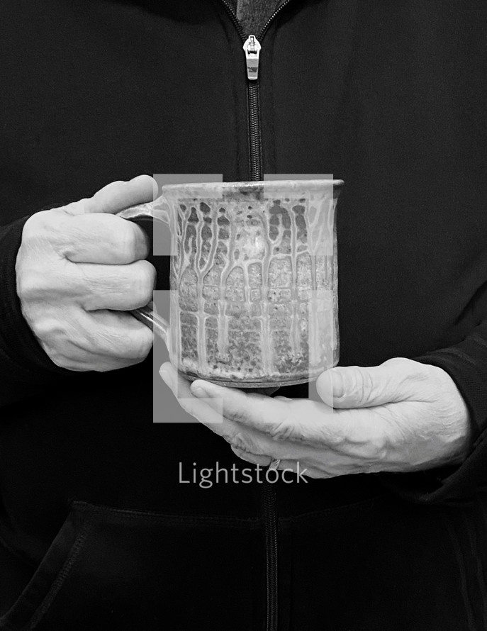 hands of a man holding a mug - black and white photo