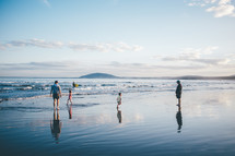 family walking on wet sand at the beach 