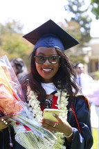 a smiling graduate holding flowers 