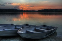 boat resting on the shore of a lake at sunset 