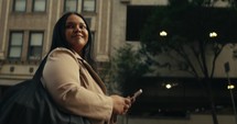 Young business woman walking around the city using her phone and laptop