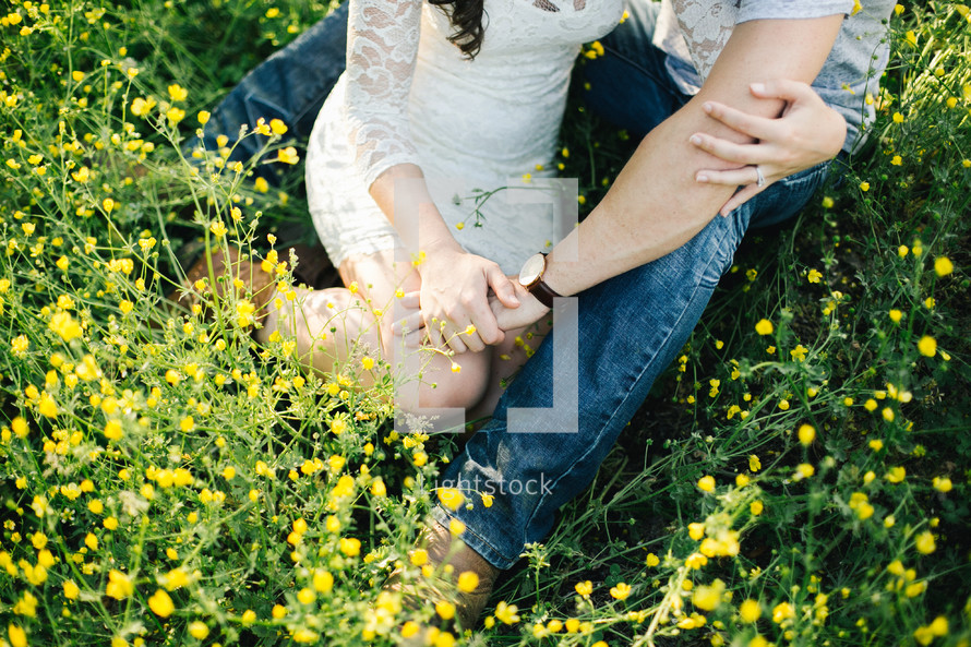 a couple sitting in a meadow of yellow flowers 